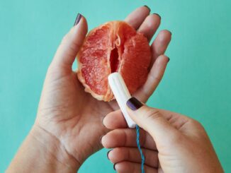woman holding ripe grapefruit and feminine tampon